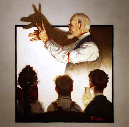 painting of three people watching an older man make shadow puppets
